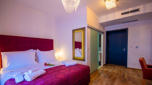 Ett hotellrum med en stor säng, en spegel, en dörr och en stol.