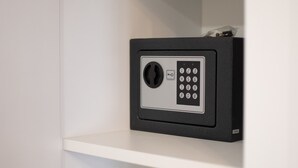 A black safe with a keypad on a white shelf. - Center Luxury Rooms 3 (Split)