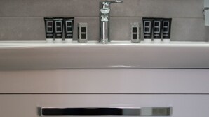 A bathroom with a modern faucet, two drawers, and a shelf with toiletries. - Center Luxury Rooms 3 (Split)