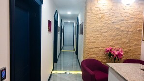 A hotel lobby with a marble floor, a reception desk, a stone accent wall, and a chandelier. - Center Luxury Rooms 3 (Split)