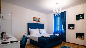 A modern hotel room with a large bed, a desk, and a chandelier. - Center Luxury Rooms 3 (Split)
