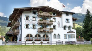 Ein traditionelles Gebäude im alpinen Stil mit mehreren Balkonen, einem Restaurantschild und Blick auf die Berge.