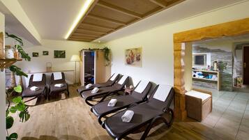 Relax in a serene spa room with a comfortable seating area, wall-mounted shelf, and large window.