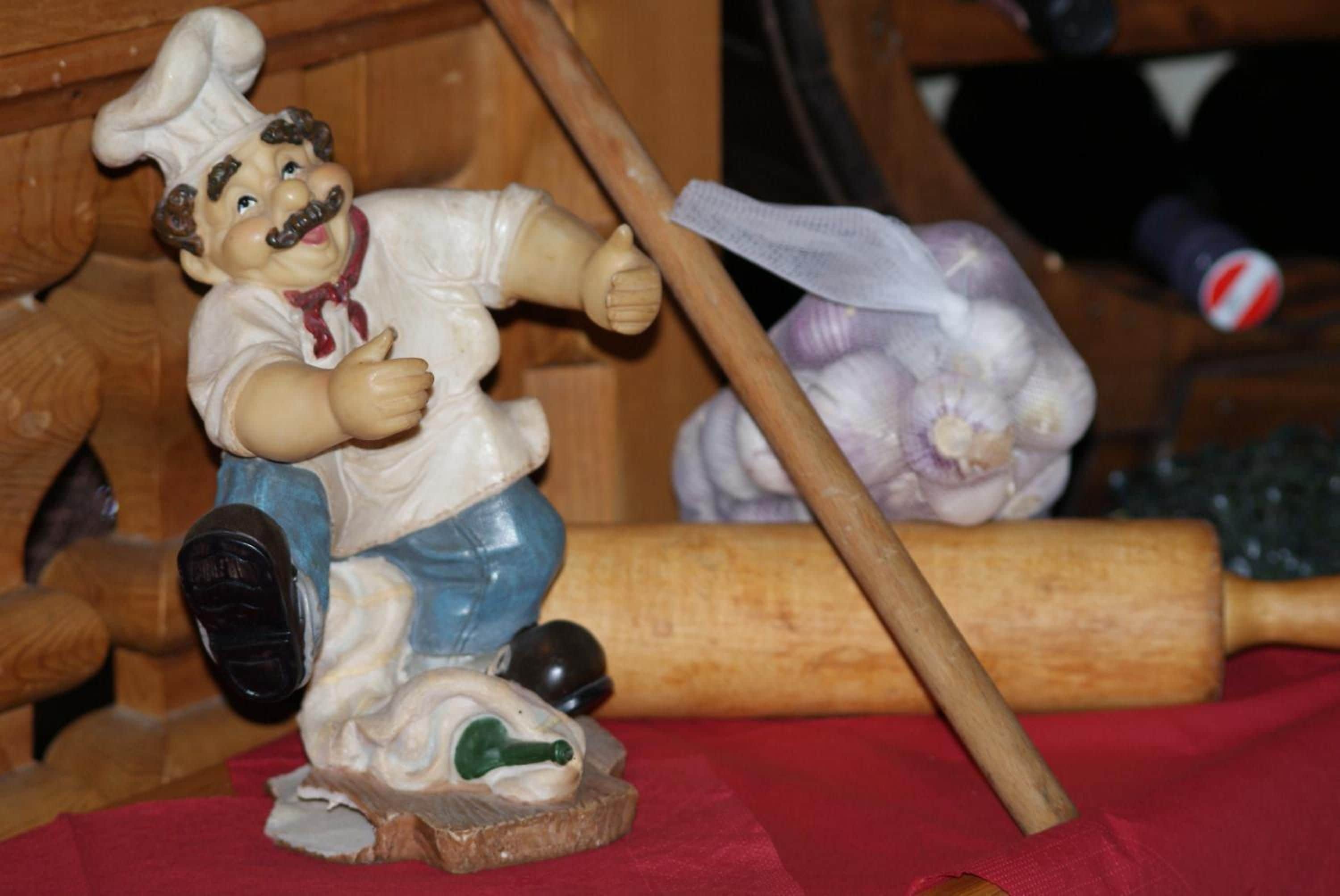 A figurine of a chef with a rolling pin and a vegetable.