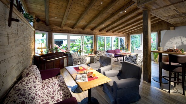 Ein gemütliches Zimmer mit Klavier, Sitzgelegenheiten und großen Fenstern.