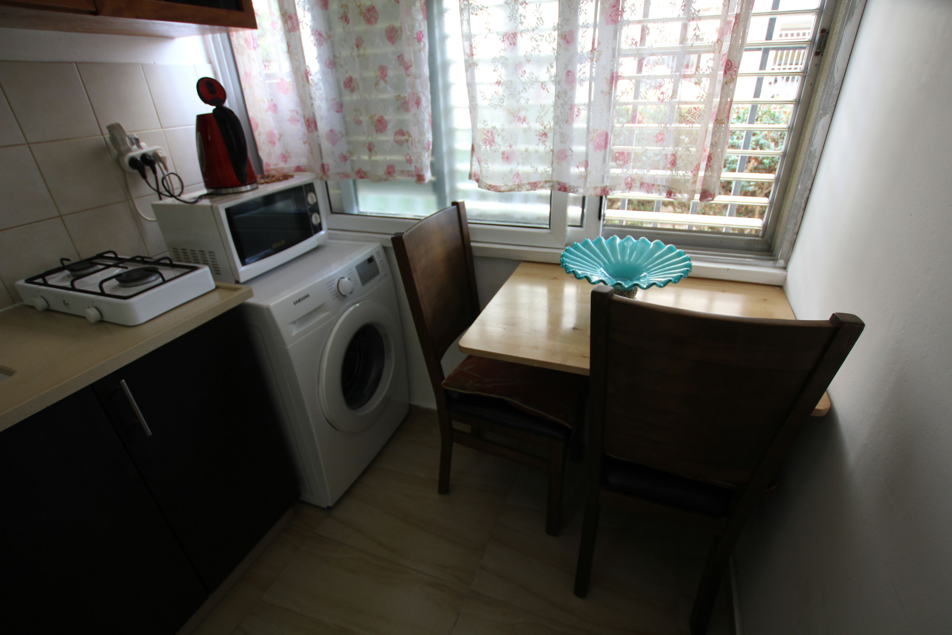 A compact kitchen with a washing machine, a microwave, and a gas stove.