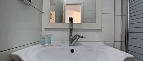A white bathroom sink with a mirror above it, a faucet, and a soap dispenser.