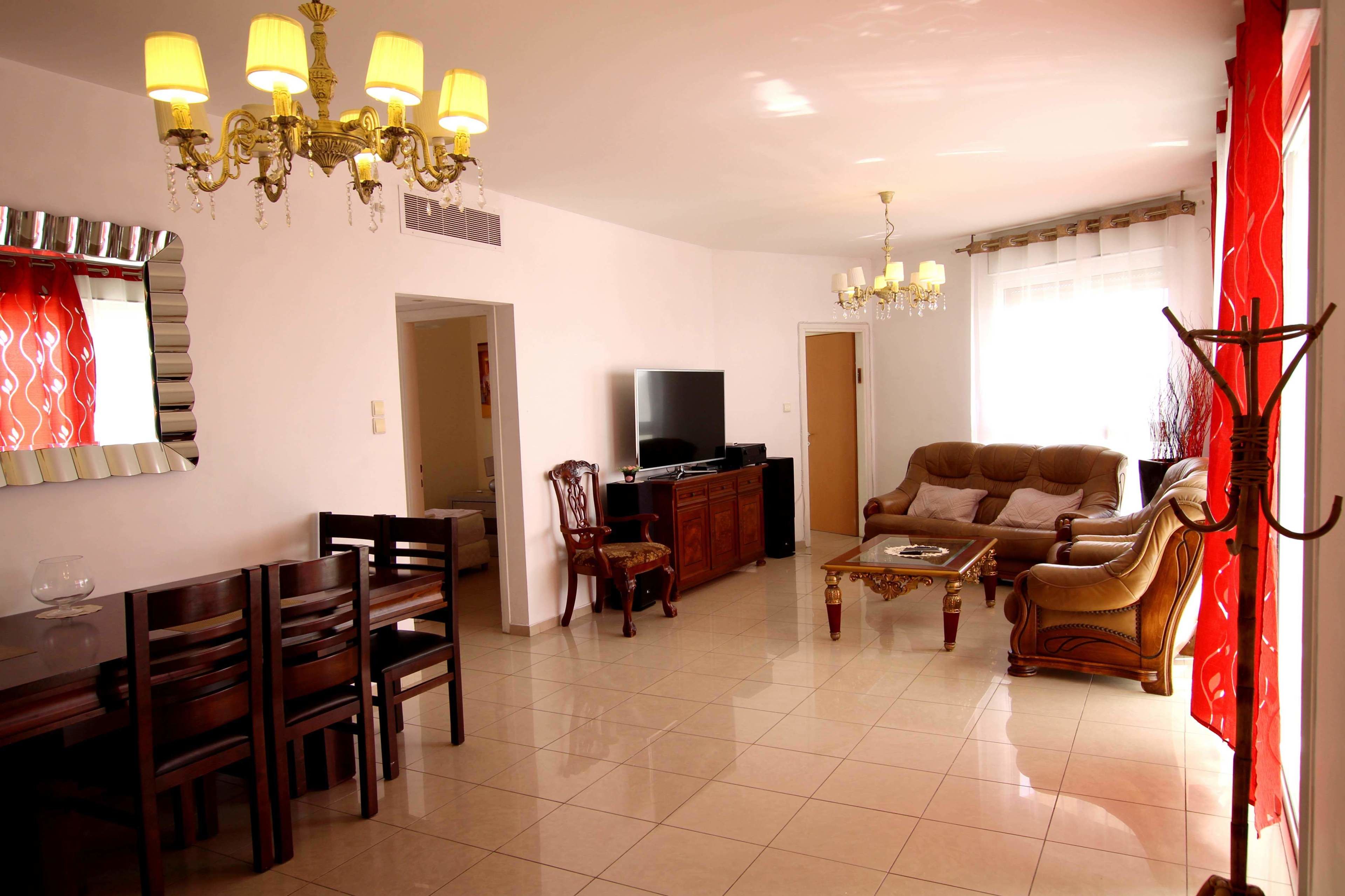 A spacious living room with a television, a sofa, and a dining area with chairs and a table.