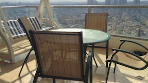 A balcony with a table and chairs, offering a city view. - Arendalzrail Apartments - Yoseftal Street 3 (Bat Yam)