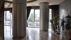 A spacious lobby with large columns, a view of the outdoors, and several potted plants. - Arendalzrail Apartments - Yoseftal Street 3 (Bat Yam)