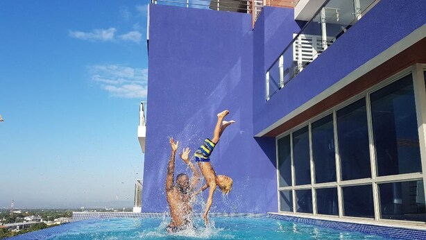 A swimming pool with a view of a building with large windows and a blue exterior. - Ultra Luxury Apartment at  20 South (Kingston)