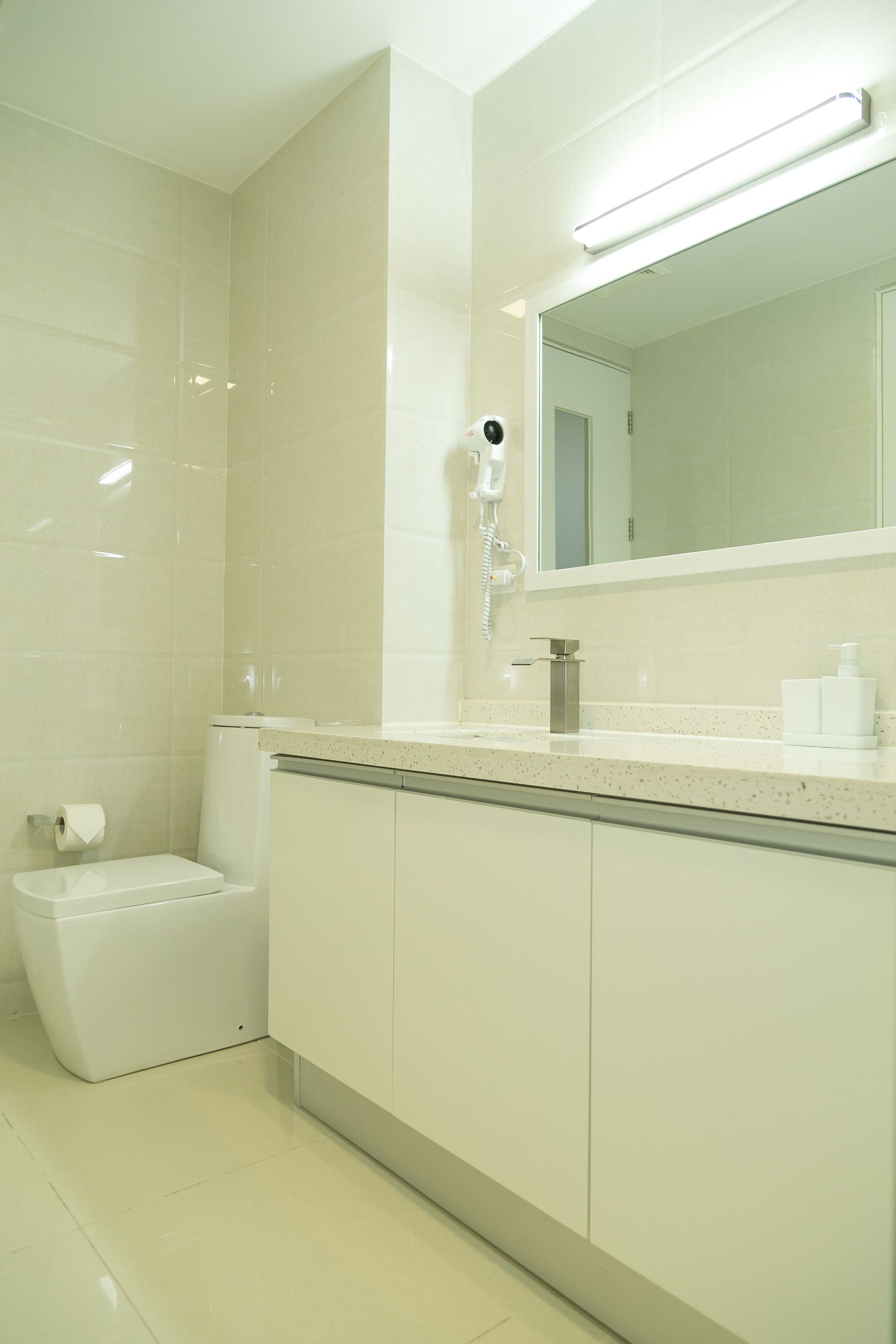 Un baño moderno con inodoro, lavamanos y espejo.