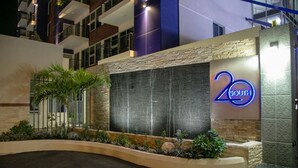 A modern hotel entrance with a stone facade, a water feature, and a neon sign indicating the hotel name. - Ultra Luxury Apartment at  20 South (Kingston)