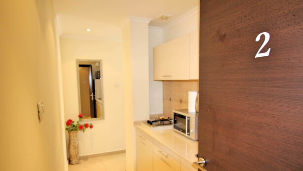 Un pasillo que da a una cocina con microondas, armarios y una puerta de madera con el número 2.