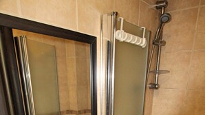 Un baño con lavamanos blanco, un espejo y zona de ducha.