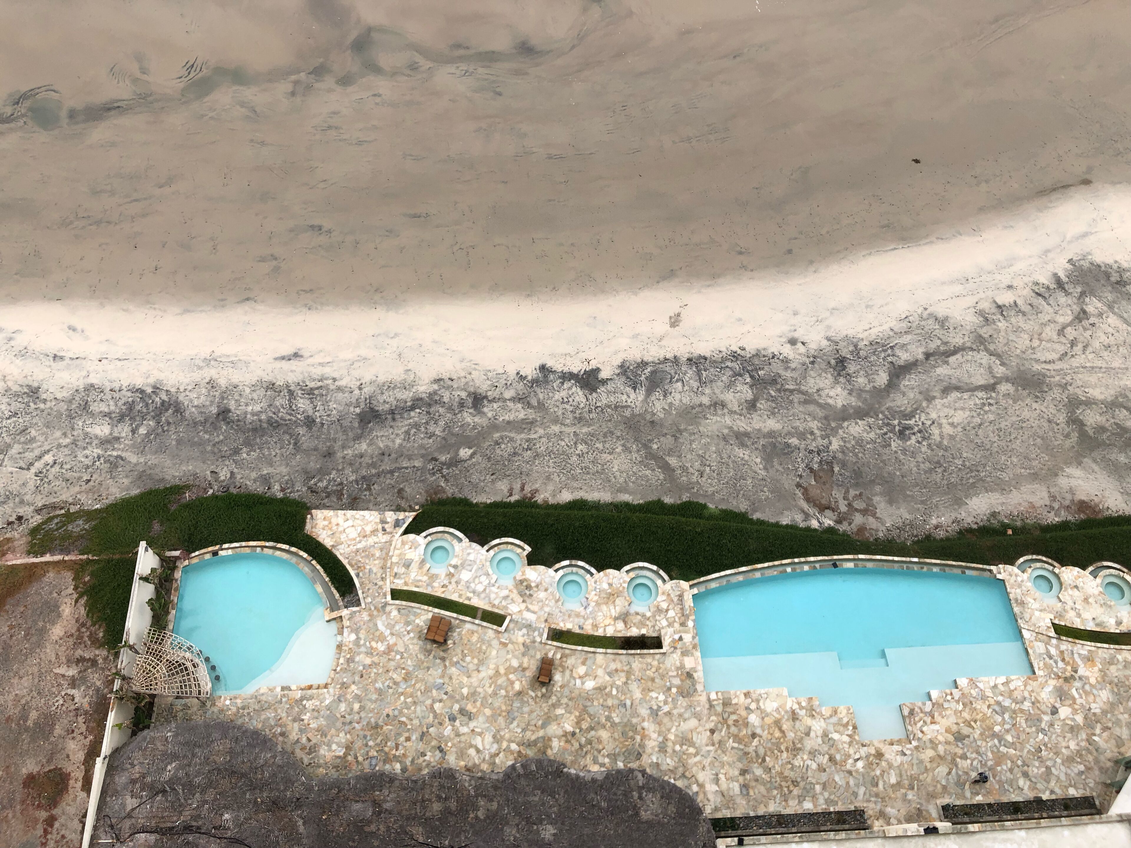 Area piscina con più piscine, circondata da un muro in pietra e vegetazione.