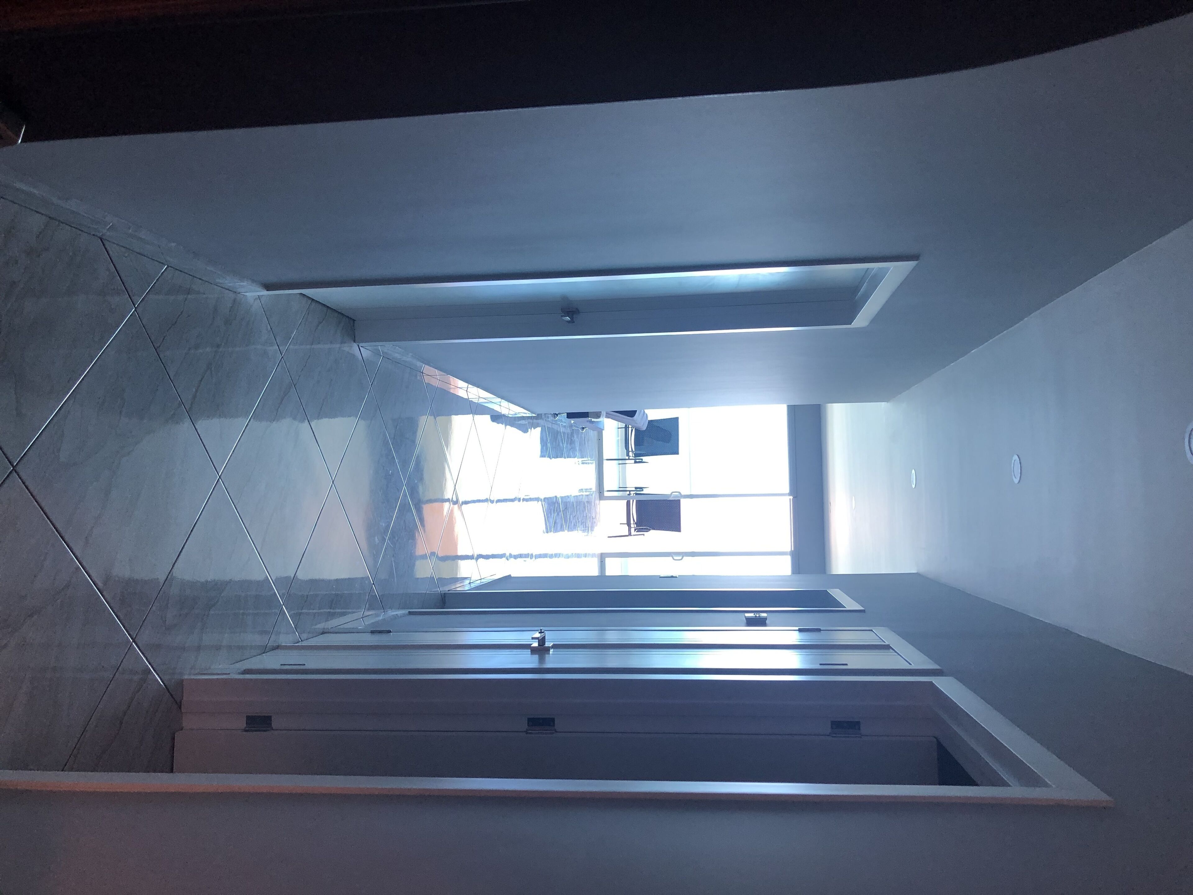 Ein modernes Interieur mit Glastrennwand, einem an der Decke befestigten Projektor und Blick ins Freie.