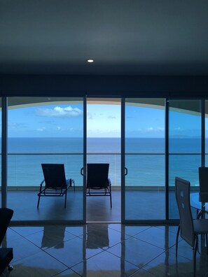 Ein Balkon mit zwei Stühlen vor einem großen Fenster mit Blick auf das Meer.