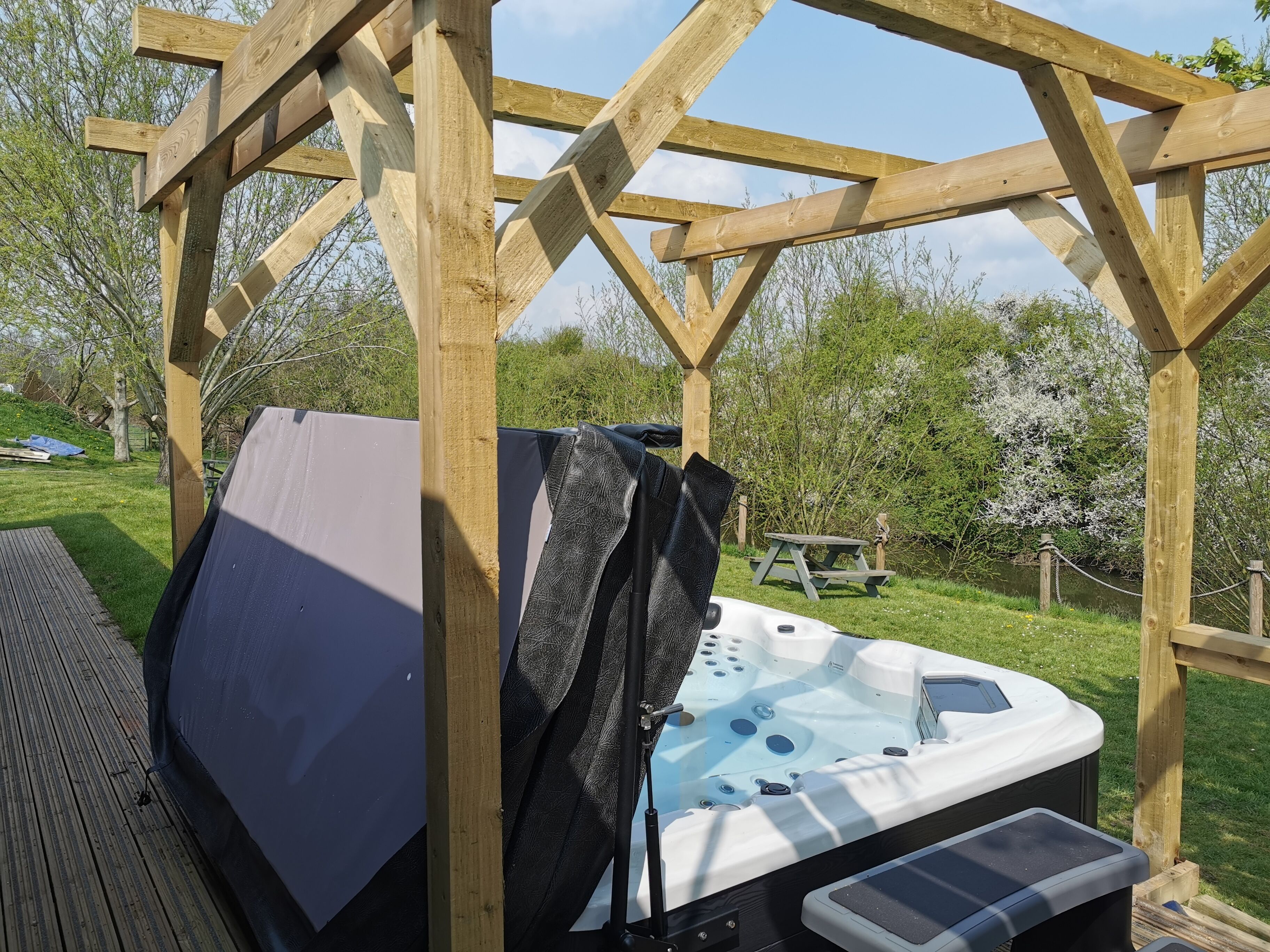 Una estructura de pérgola de madera con un jacuzzi debajo.