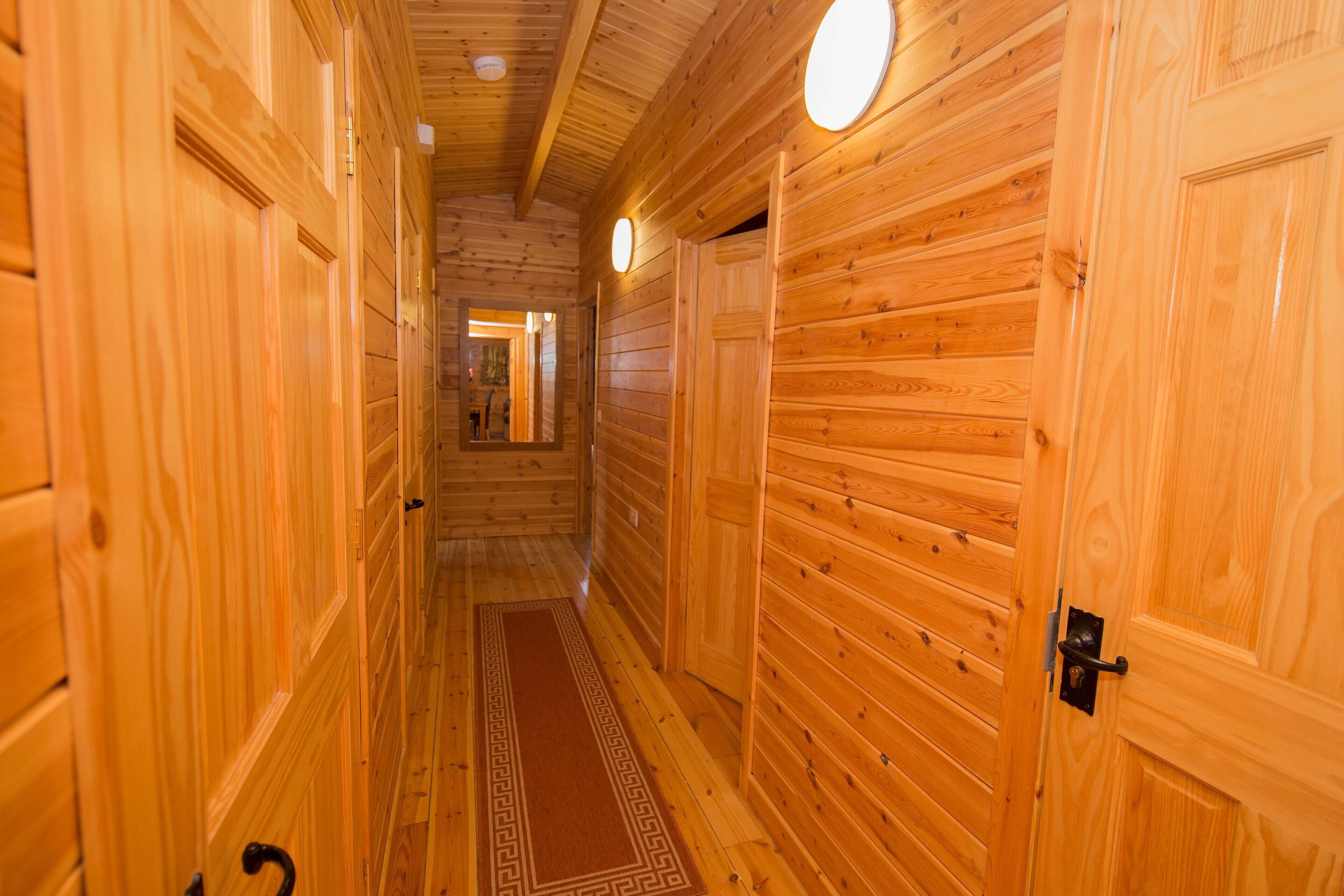 Un pasillo de madera con puertas y una alfombra.