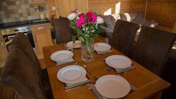 A dining table set with plates, cutlery, and a vase of flowers in a wooden interior.