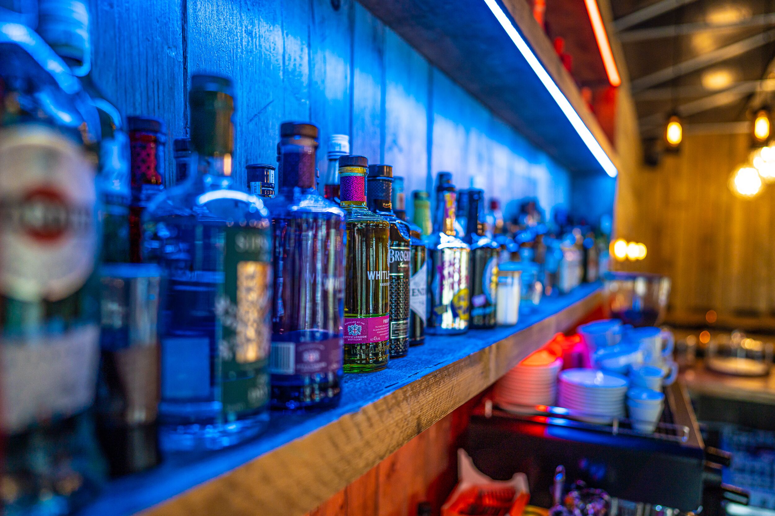 Un bar con una estantería de madera que exhibe diversas botellas de alcohol.