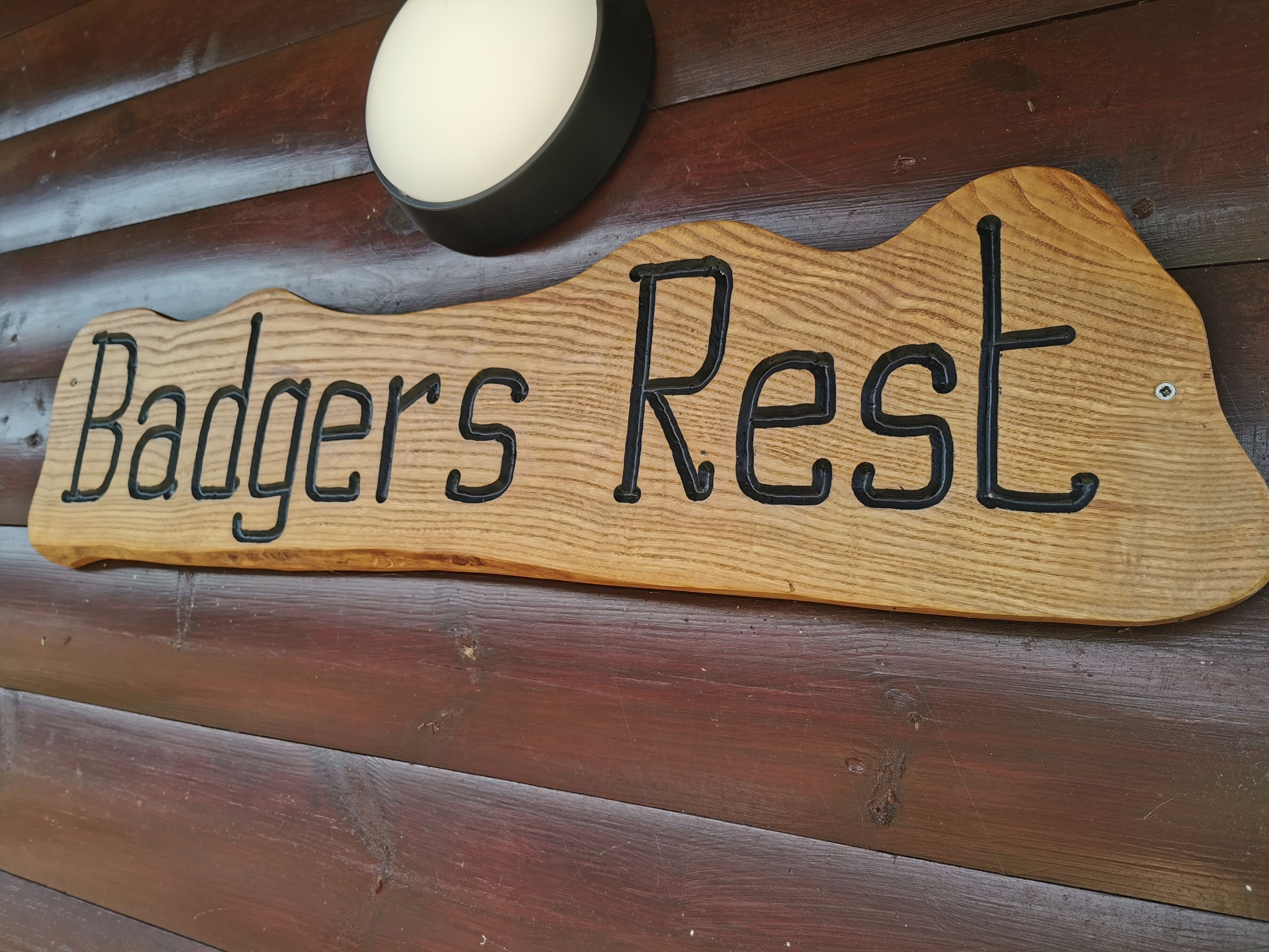 Une enseigne en bois portant l’inscription « Badgers Rest » est fixée à un mur en bois.