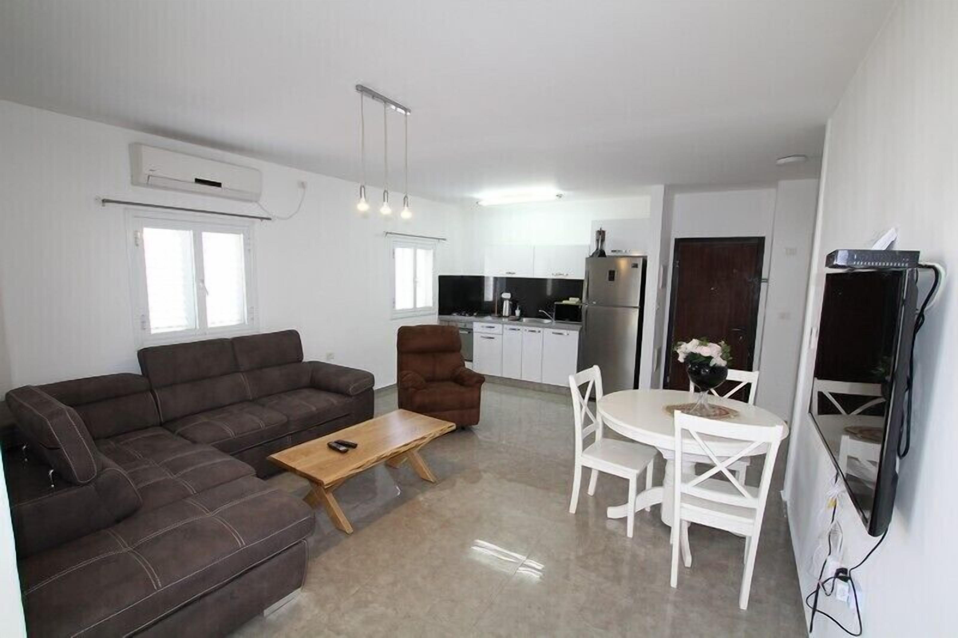 A modern living room with a sofa, coffee table, and dining area with chairs.