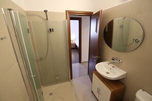 A bathroom with a glass-enclosed shower, a sink with a mirror, and a toilet. - Arendalzrail Apartment - Hertsel St. 4 (Bat Yam)