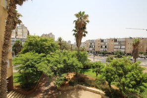 A residential area with multiple-story buildings, palm trees, and a road with cars. - Arendalzrail Apartment - Hertsel St. 4 (Bat Yam)