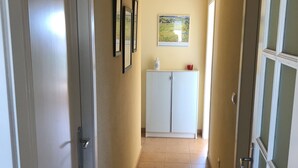 A hallway with a tiled floor, white doors, and a cabinet with a picture frame and a red object on top. - Attic Lo Pagan in Mar Menor (San Pedro del Pinatar)