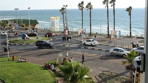 A coastal intersection with palm trees, a roundabout, and a view of the ocean.