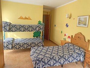 A room with bunk beds, a wooden nightstand, a wall with a painting, and a door leading to another room. - Hotel Antic (La Cortinada)