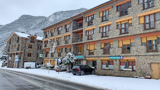 Un edificio de varios pisos de piedra, con letrero de hotel y restaurante.