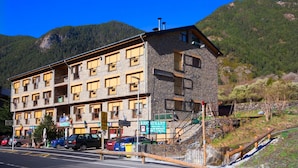 Un hotel de varios pisos con fachada de piedra, balcones y un letrero de restaurante.