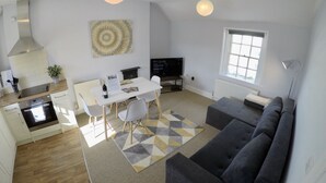 A modern kitchen with a built-in oven and a dining area with a white table and chairs. - The King's Meadery (Bath)