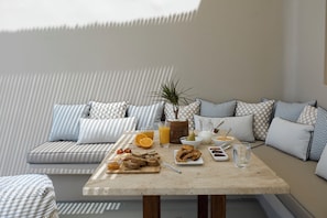 Un comedor con una mesa dispuesta para el desayuno, que incluye pan, fruta y bebidas.