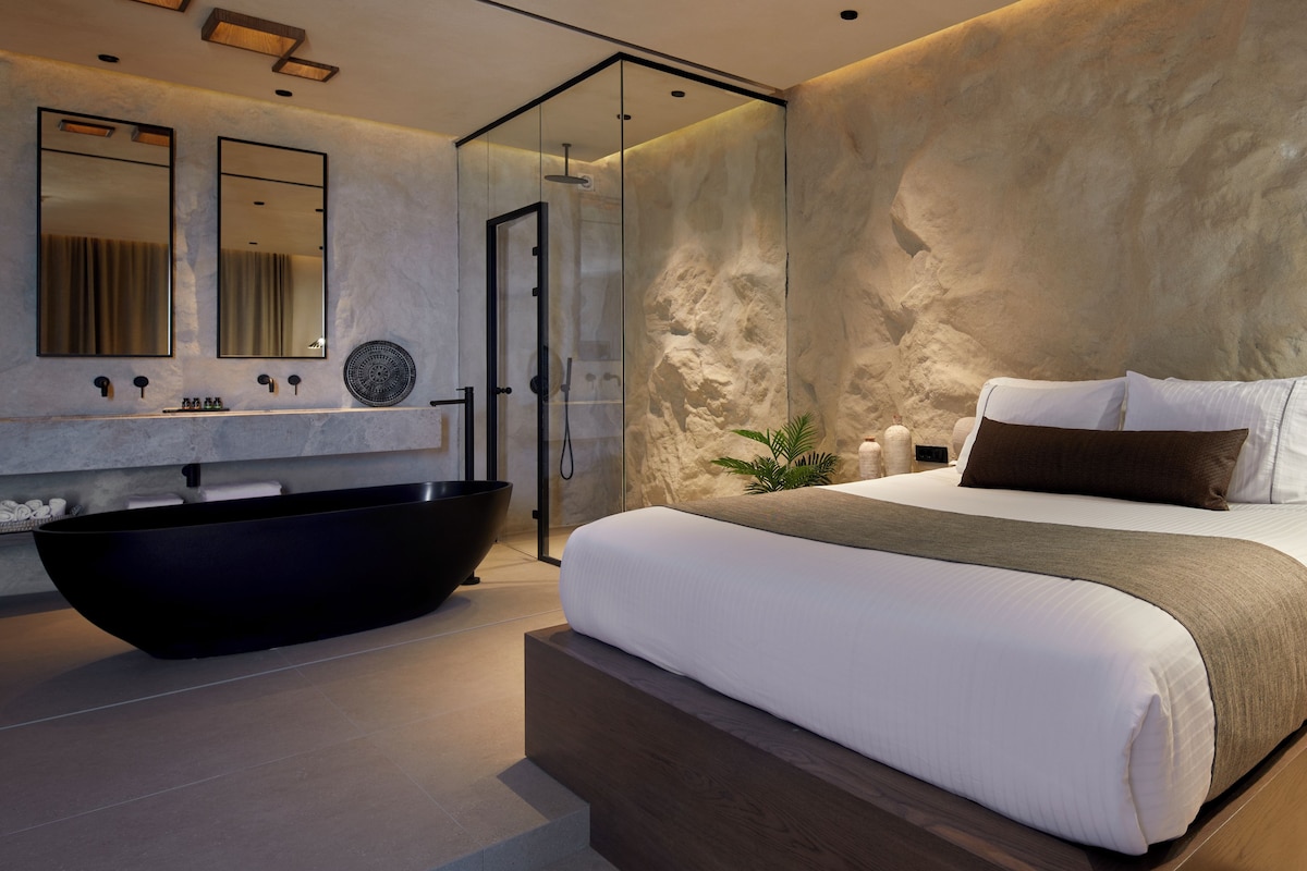 Un baño moderno con una bañera negra grande, lavamanos doble y ducha con cerramiento de vidrio.