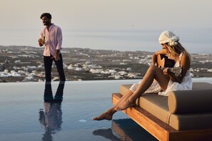 Una pareja junto a una piscina infinita con vistas al paisaje costero.