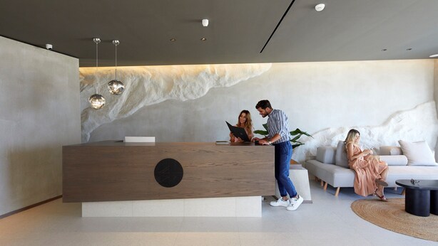 Un espace d’accueil comprenant un comptoir de réception en bois, un canapé et une table basse.