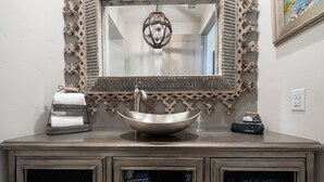 Une salle de bain dotée d’un grand miroir, d’un lavabo sur colonne et d’un meuble en bois avec des portes en verre.