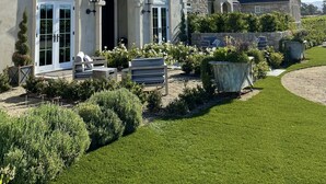 Une grande maison avec une pelouse bien entretenue, un espace salon extérieur et une montgolfière dans le ciel.