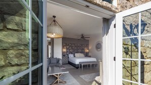 Une chambre moderne avec un mur en pierre, un lit, un bureau et un luminaire suspendu.