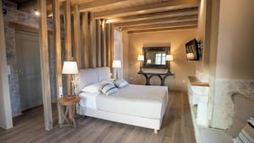 Un dormitorio con una cama grande, vigas de madera, paredes de piedra y una chimenea.