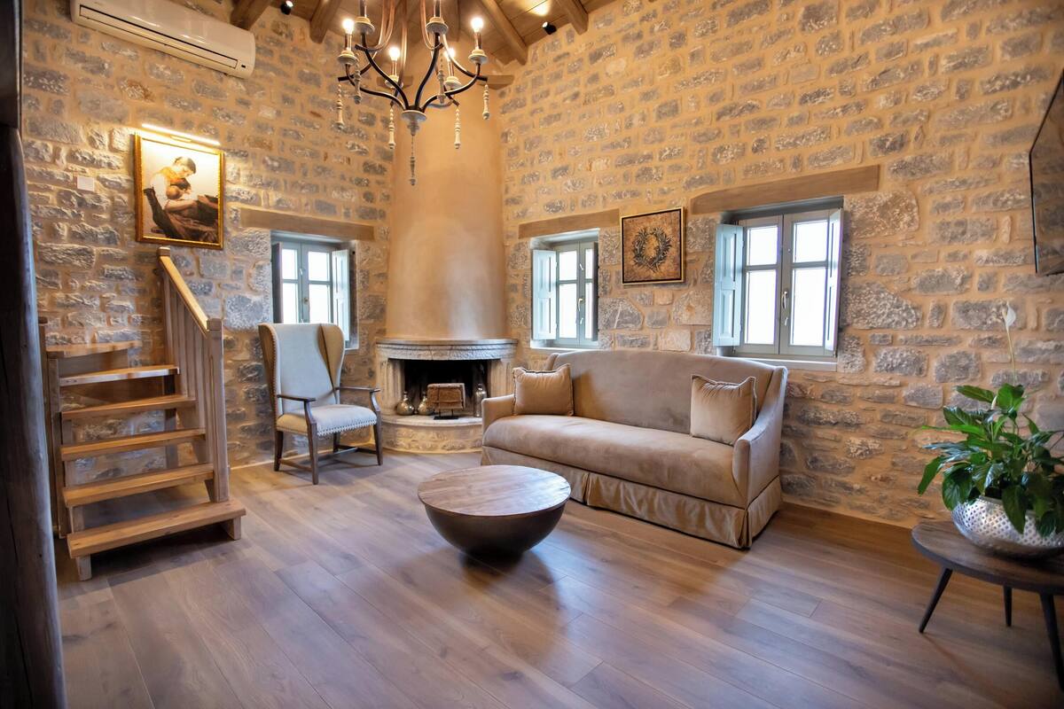 A cozy living room with a stone wall, a fireplace, a sofa, and a coffee table.