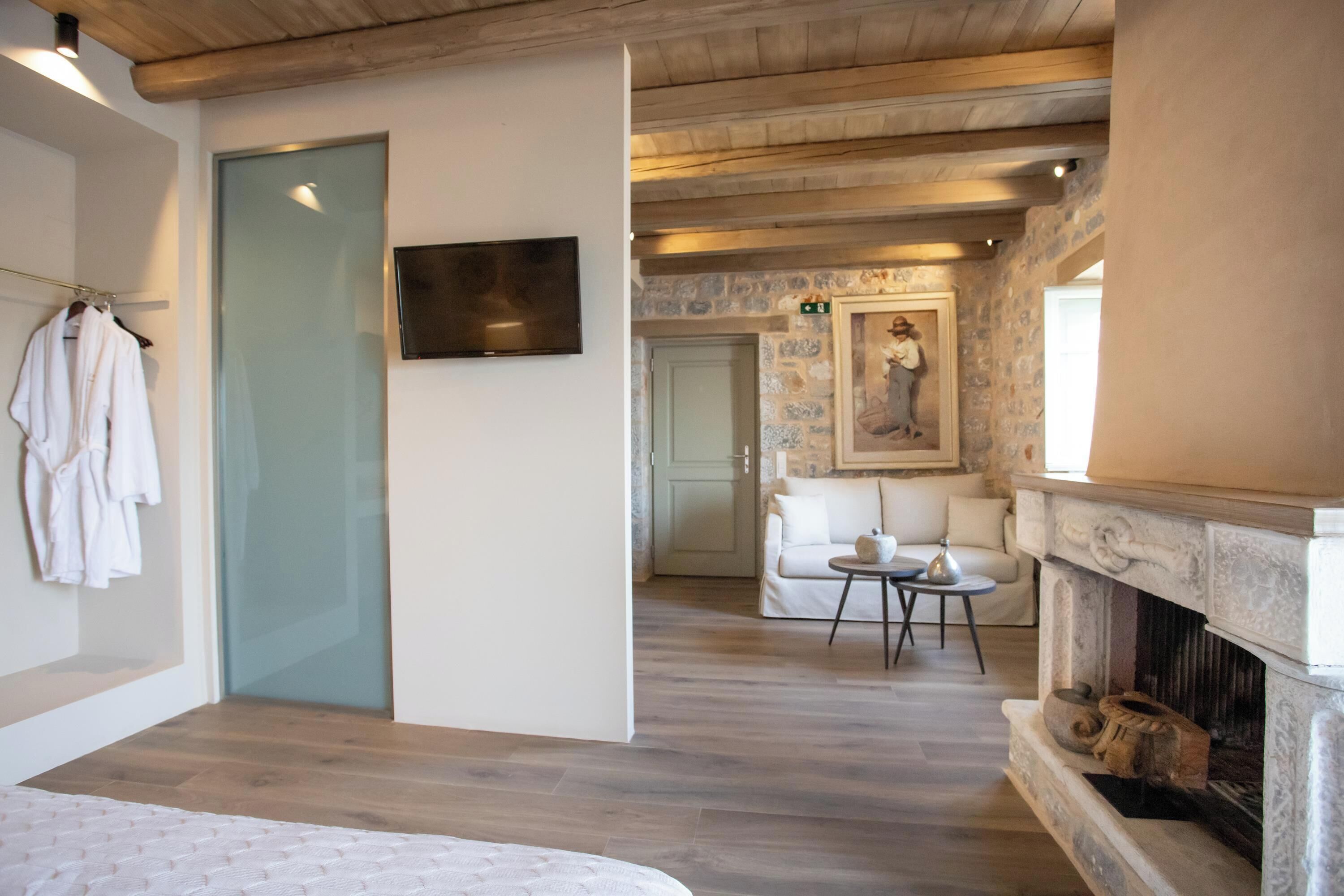 Una habitación moderna con cama, televisión, chimenea y pared de piedra.
