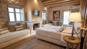 Une chambre confortable avec un mur en pierre, une cheminée, un lit et un téléviseur.