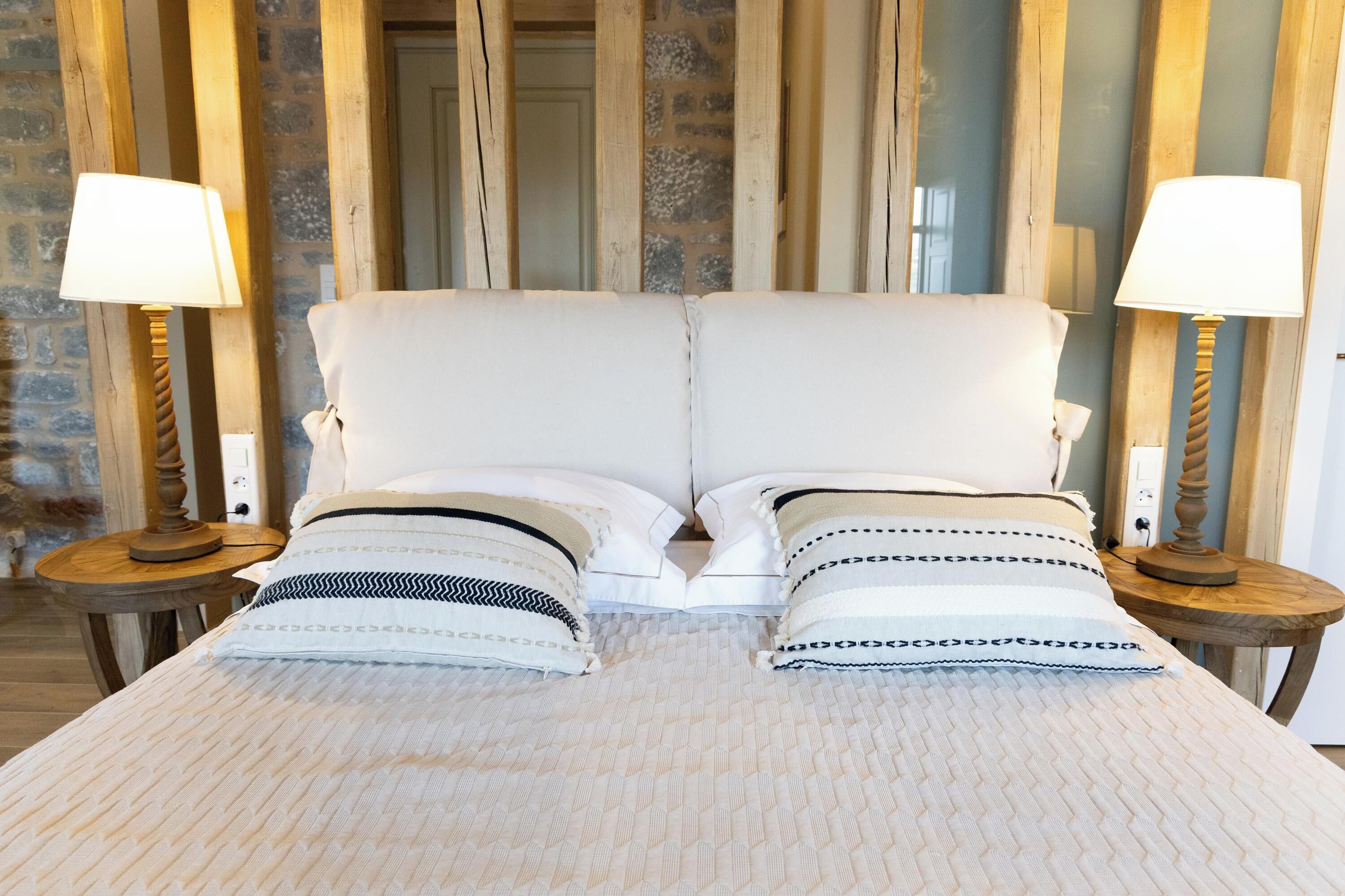 A double bed with white bedding and two bedside tables with lamps.