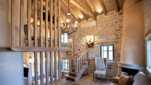 Un vaste espace de vie agrémenté d’un escalier en bois, d’une cheminée et d’un lustre.