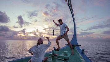 Duas pessoas num barco com o pôr do sol ao fundo.